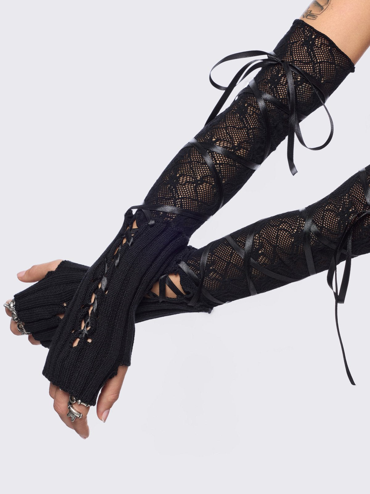 Black knit arm warmers featuring fishnet layer and lace up details.