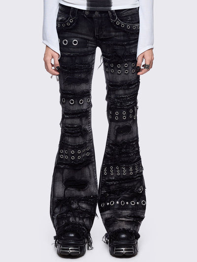 Black washed flare jeans featuring heavy distressed and shedded, eyelet, piercing and stud details. 