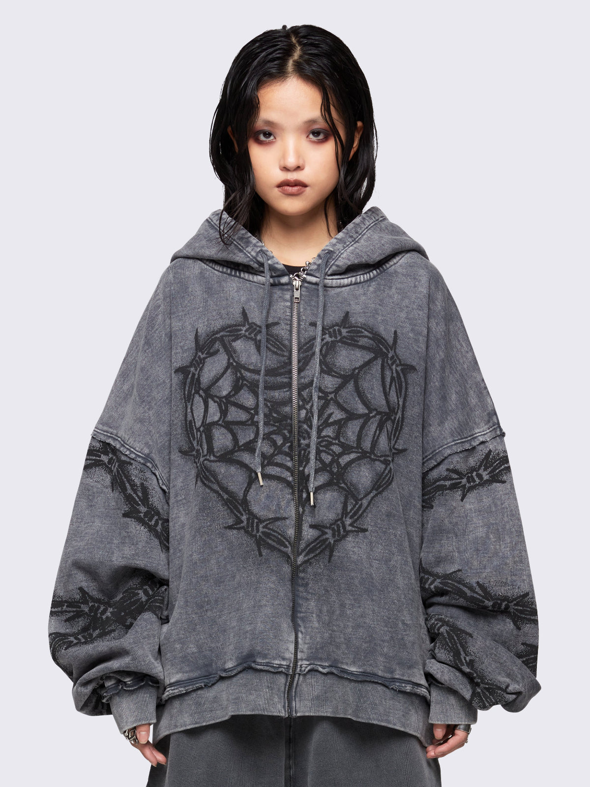 Grey distressed wash zip-up hoodie with a black barbed wire and spiderweb graphic, oversized fit, and dropped shoulders for a bold grunge aesthetic.