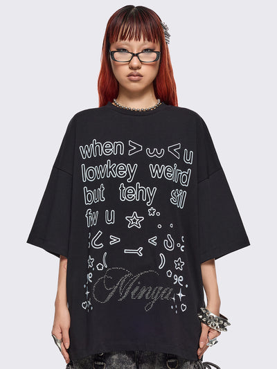 Black oversized t-shirt with "when u lowkey weird but tehy stil fw u" graphic print, kaomoji ASCII-style embroideries and stud details.