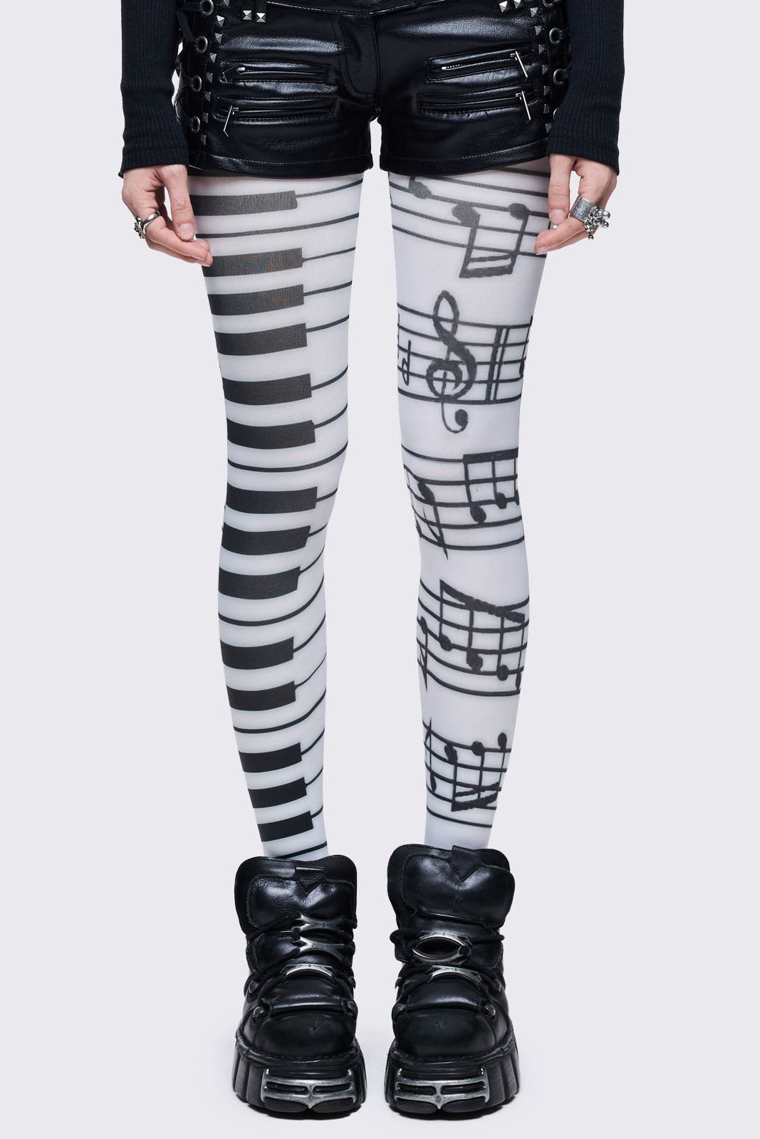 White tights featuring a split design: one leg has a black piano keyboard pattern, and the other has black musical notes and staves.