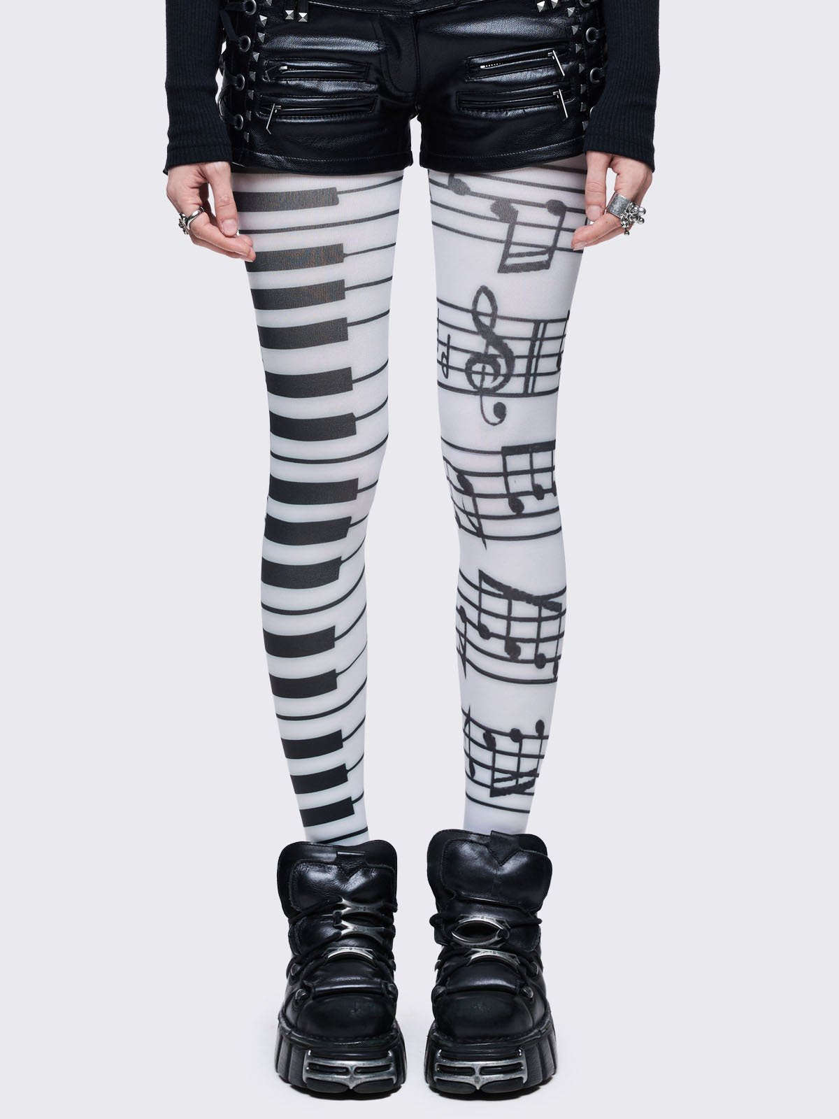 White tights featuring a split design: one leg has a black piano keyboard pattern, and the other has black musical notes and staves.
