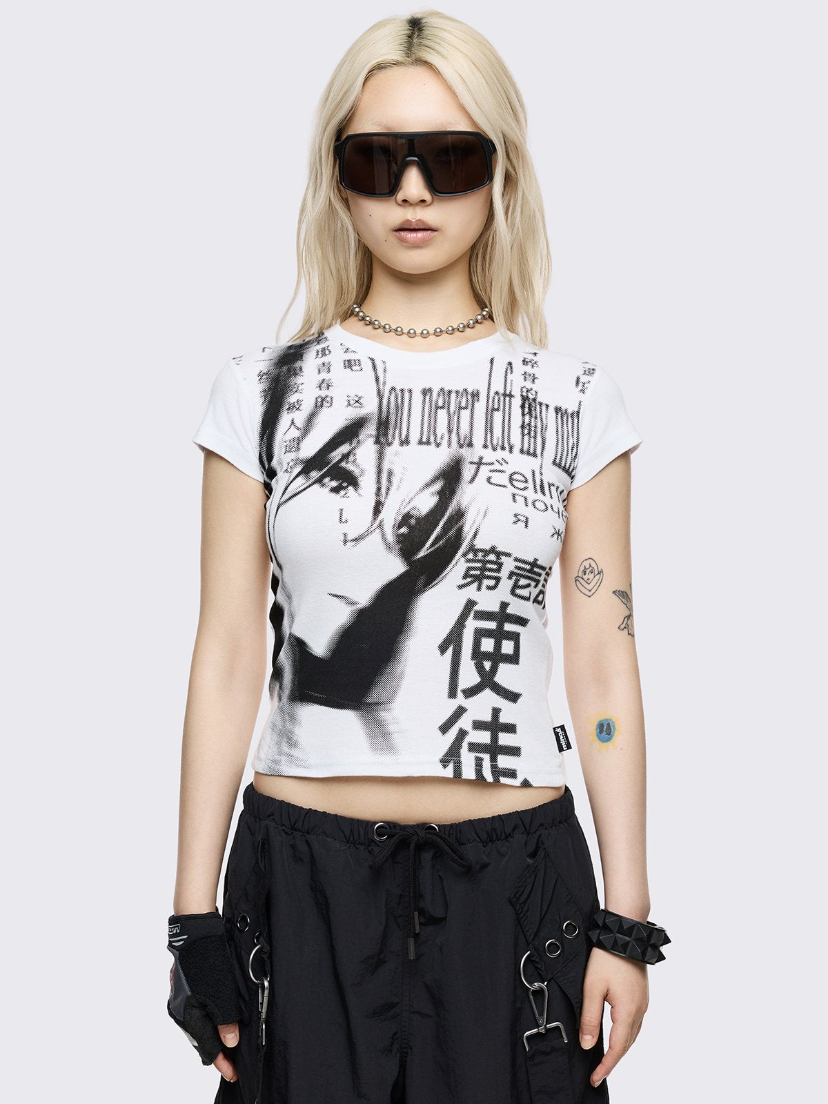 A fitted white baby tee featuring a large black monochrome graphic of a manga-style girl's face mixed with Japanese kanji and English text.