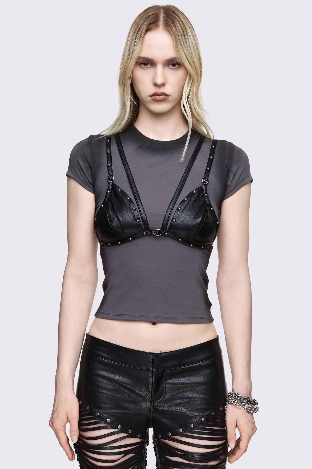 Grey washed baby tee with black faux leather bralette harness overlay, studded cups, buckle straps and slim fit.