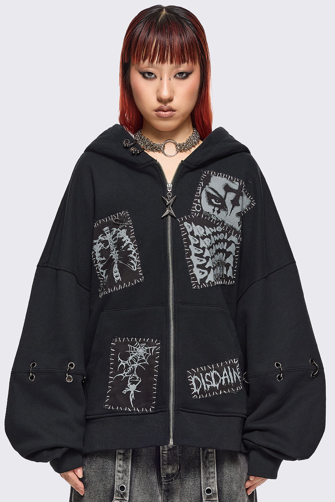 Black zip up hoodie jacket with white grunge print patches and eyelets with O-ring and piercing details.