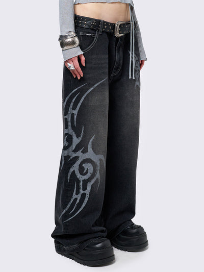 Black washed baggy jeans with a gritty grey sigilism side print, edgy white contrast stitching, regular waist, wide leg, and a relaxed, oversized fit for a grunge-inspired look.