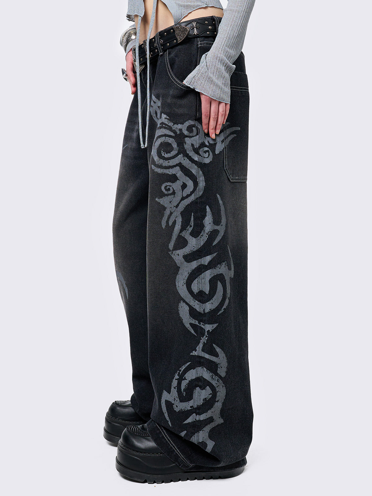 Black washed baggy jeans with a gritty grey sigilism side print, edgy white contrast stitching, regular waist, wide leg, and a relaxed, oversized fit for a grunge-inspired look.