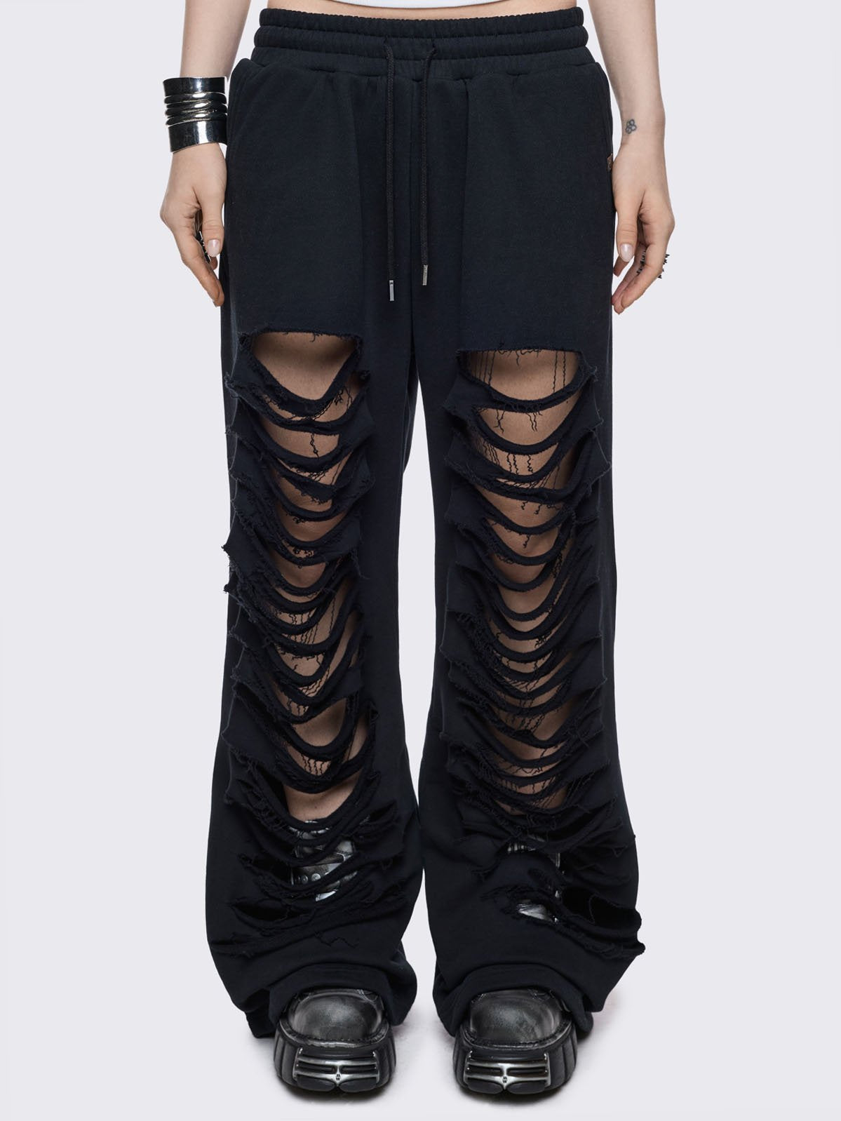 Black baggy sweatpants with slashed and frayed horizontal cut-out details.