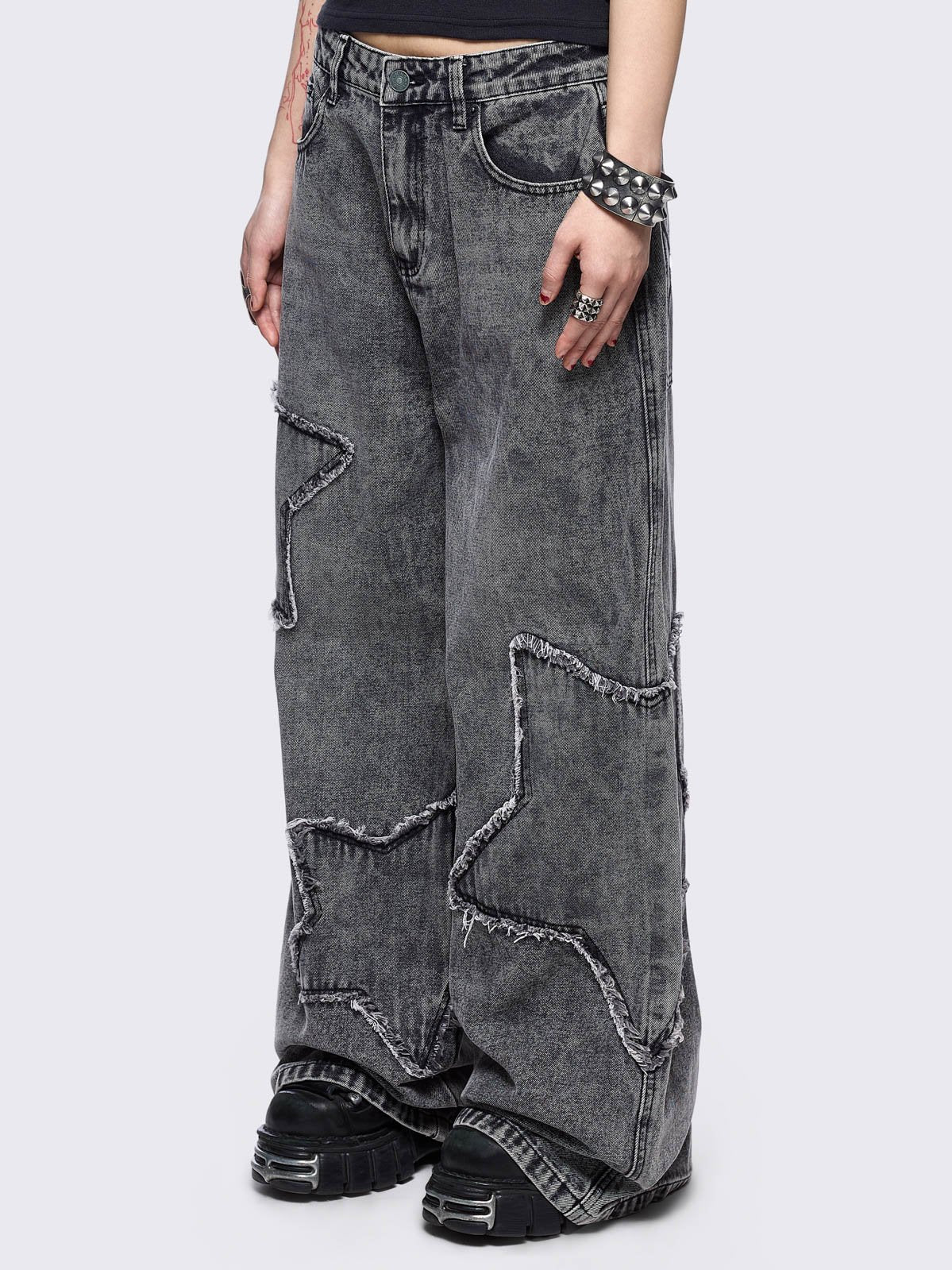 Grey washed baggy jeans with frayed star patches.