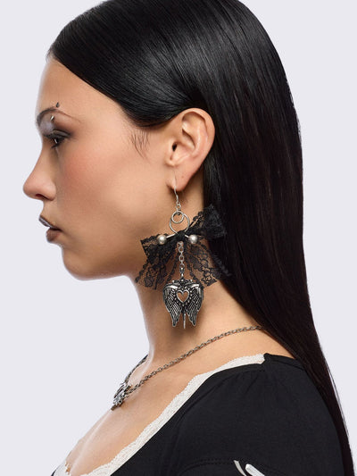 Silver dangle earrings with winged heart pendant and back lace bows and piercing details.