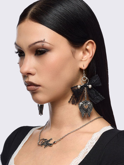 Silver dangle earrings with winged heart pendant and back lace bows and piercing details.