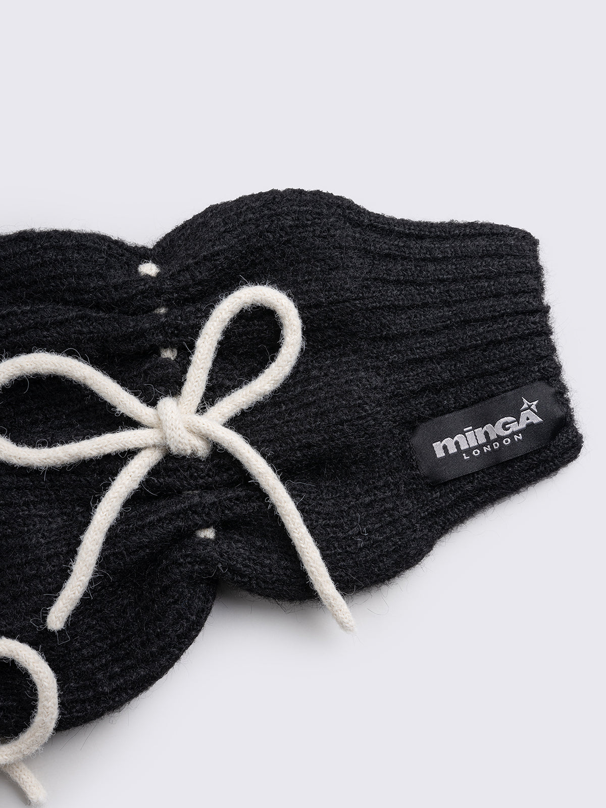 Black knitted leg warmers with white tie bows and a flared style.
