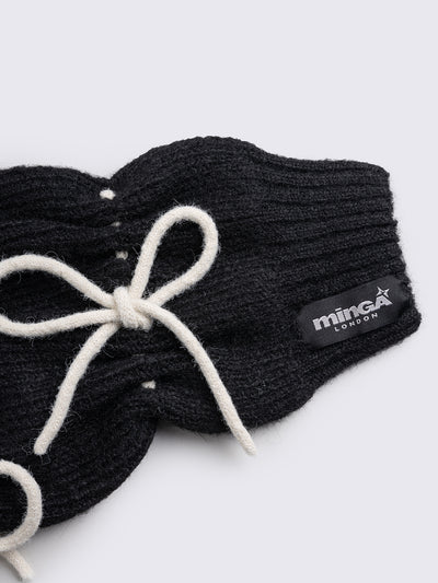Black knitted leg warmers with white tie bows and a flared style.