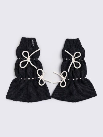 Black knitted leg warmers with white tie bows and a flared style.