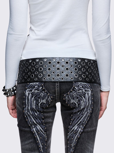 Wide black faux leather belt with multiple silver grommets/eyelets across the width, secured by a large triple-pin buckle, with a detachable star charm.