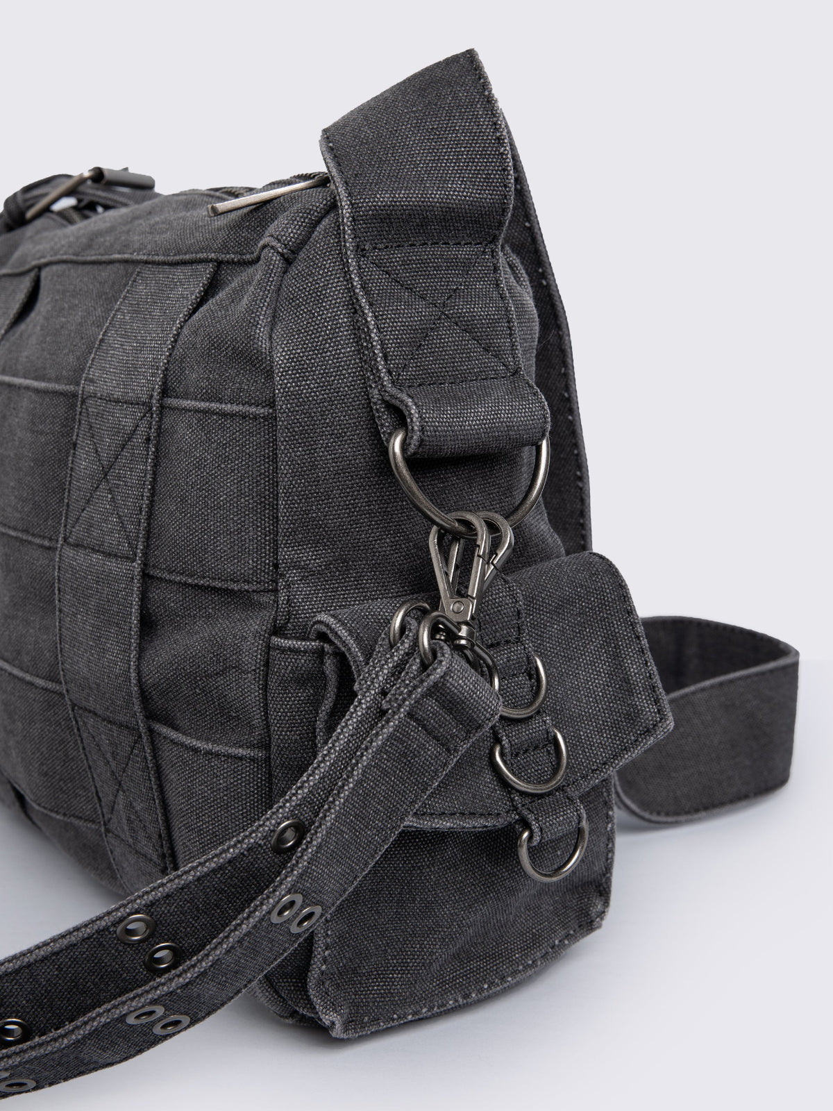 Grey washed denim crossbody bag with all over straps, studs and silver hardware details.