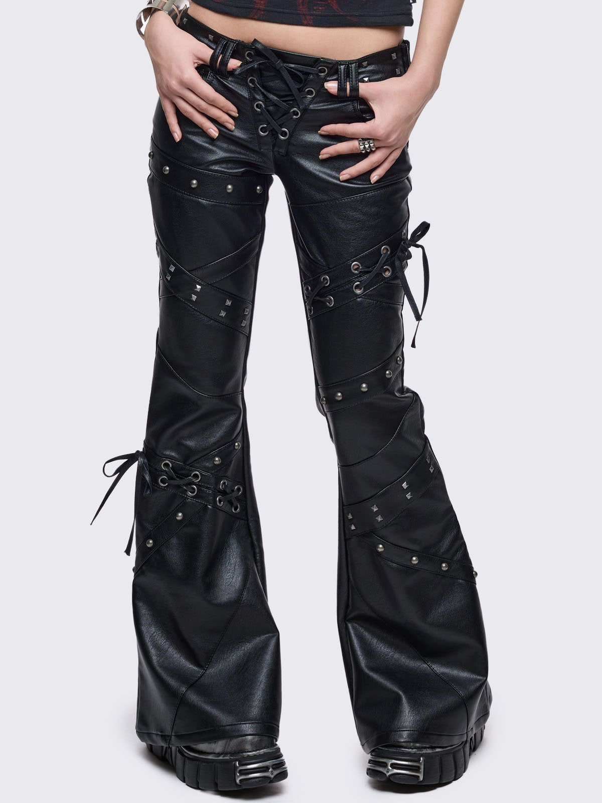 Black vegan leather flared jeans with lace up, stud and panel seam details.