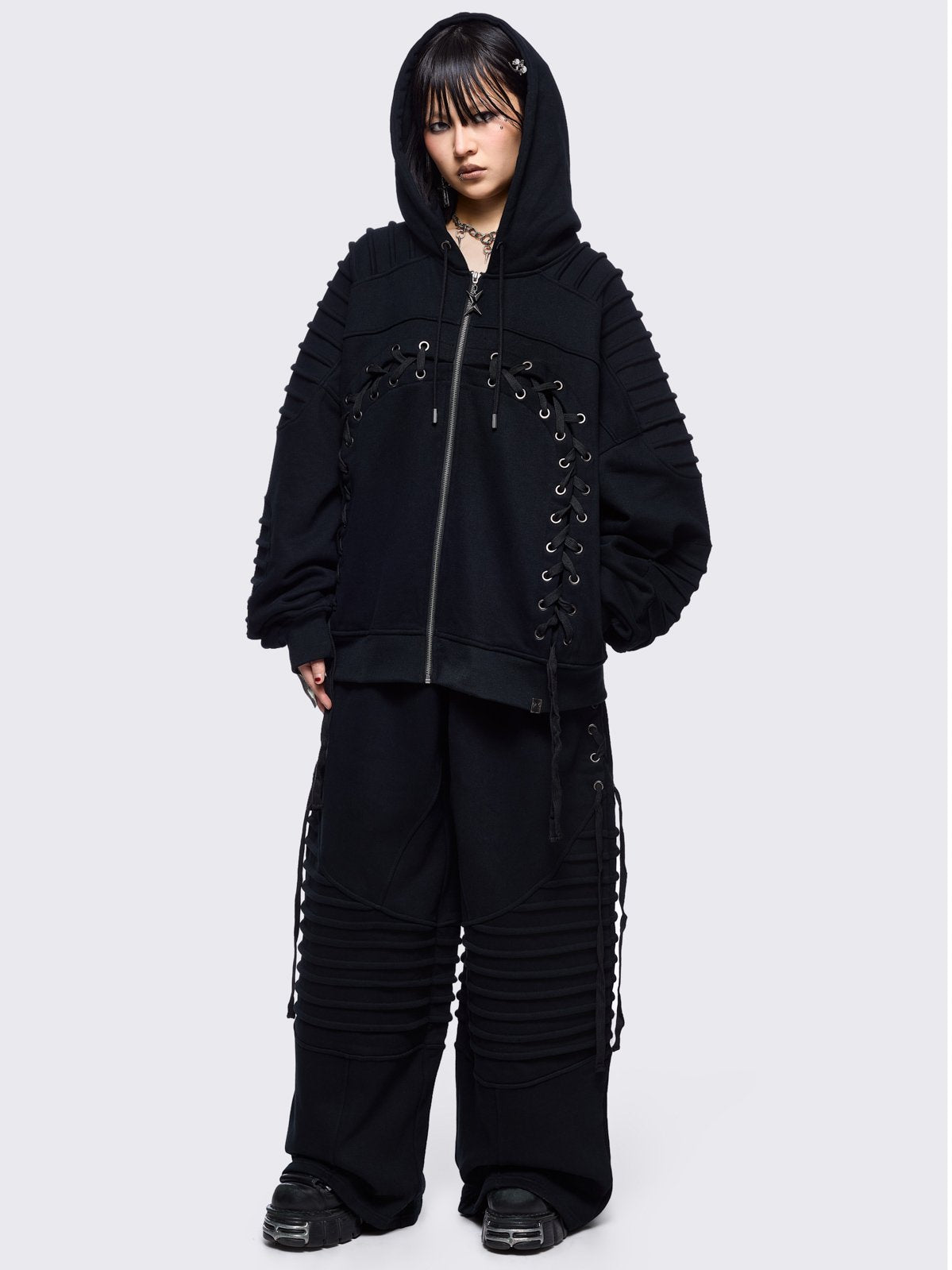 Black wide leg sweatpants featuring moto pintuck panels and lace-up details. 
