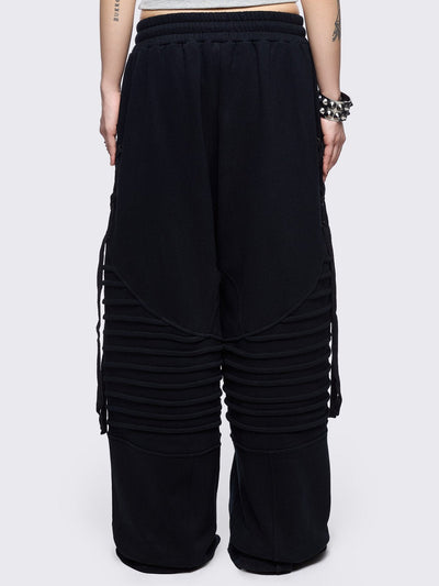 Black wide leg sweatpants featuring moto pintuck panels and lace-up details. 