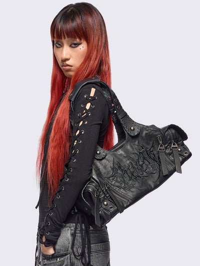 Black vegan leather shoulder bag with sigilism graphic embroidery and piercing, eyelet and stud details. 
Multiple pockets and two handles.