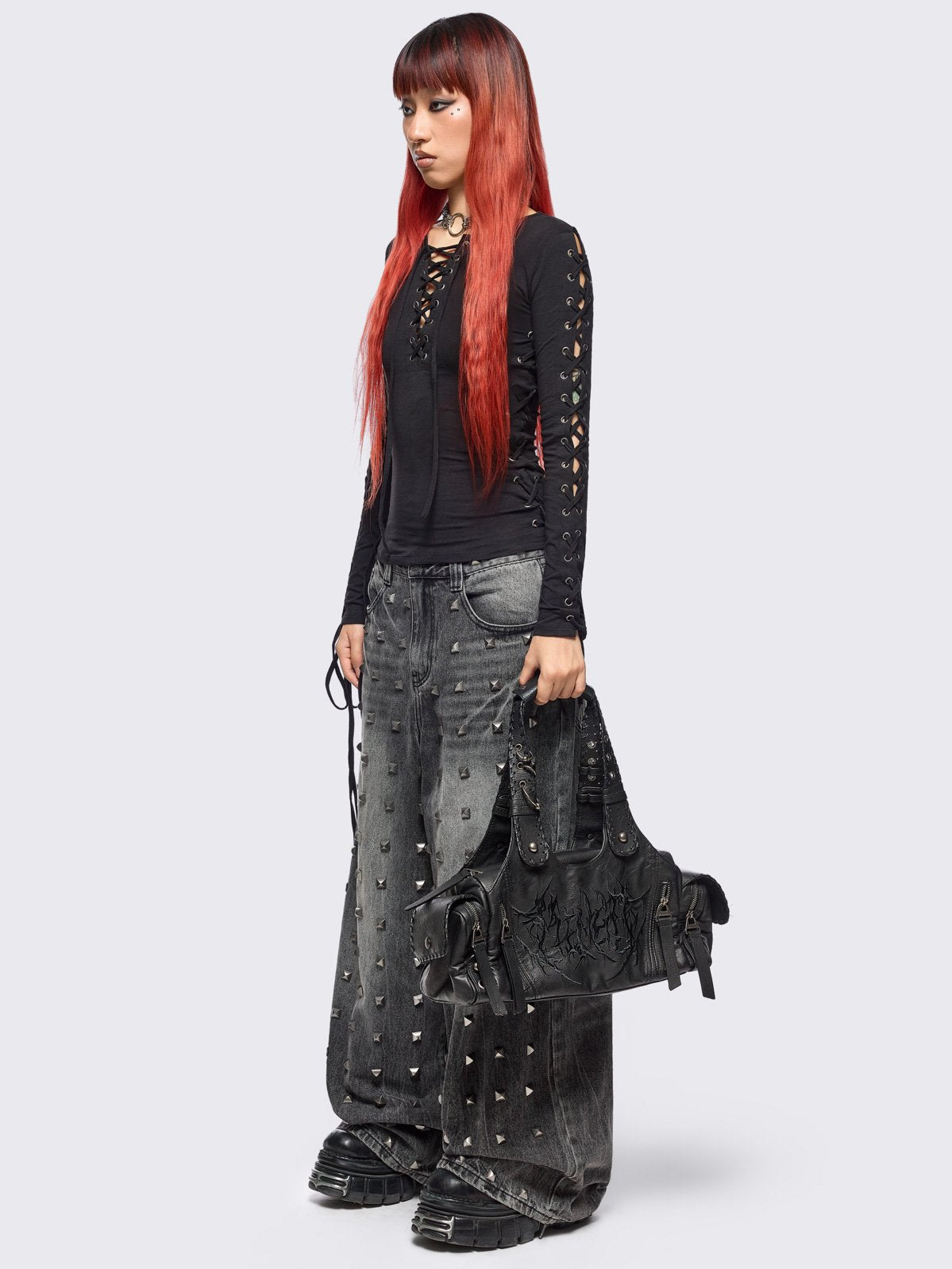 Black vegan leather shoulder bag with sigilism graphic embroidery and piercing, eyelet and stud details. 
Multiple pockets and two handles.