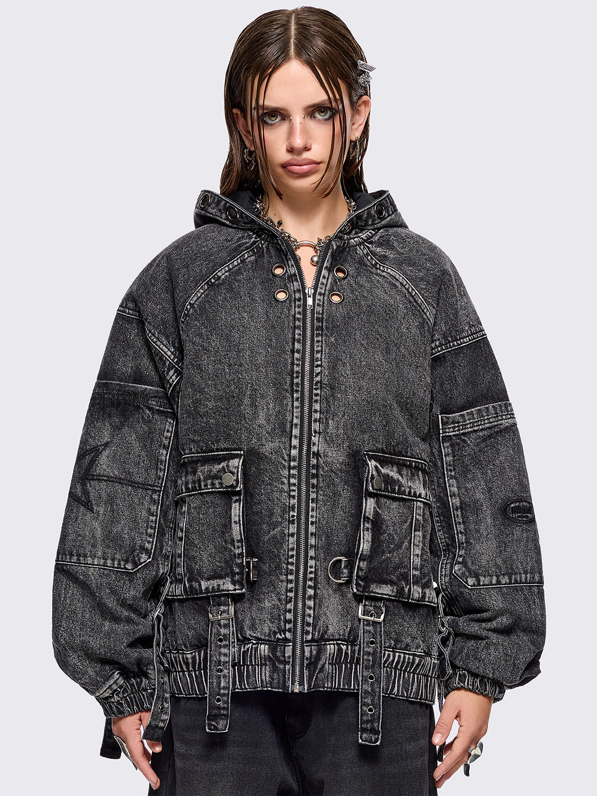 Black acid washed denim bomber jacket featuring boxy oversized fit, front flap pockets, buckle straps, eyelets, metal hardware and seams details.