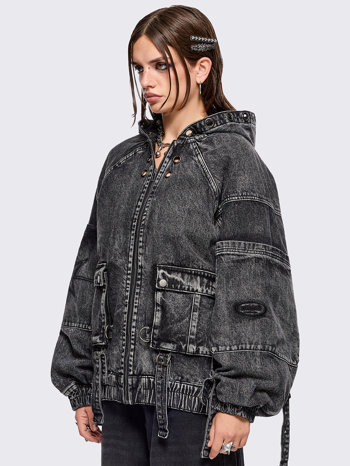 Black acid washed denim bomber jacket featuring boxy oversized fit, front flap pockets, buckle straps, eyelets, metal hardware and seams details.
