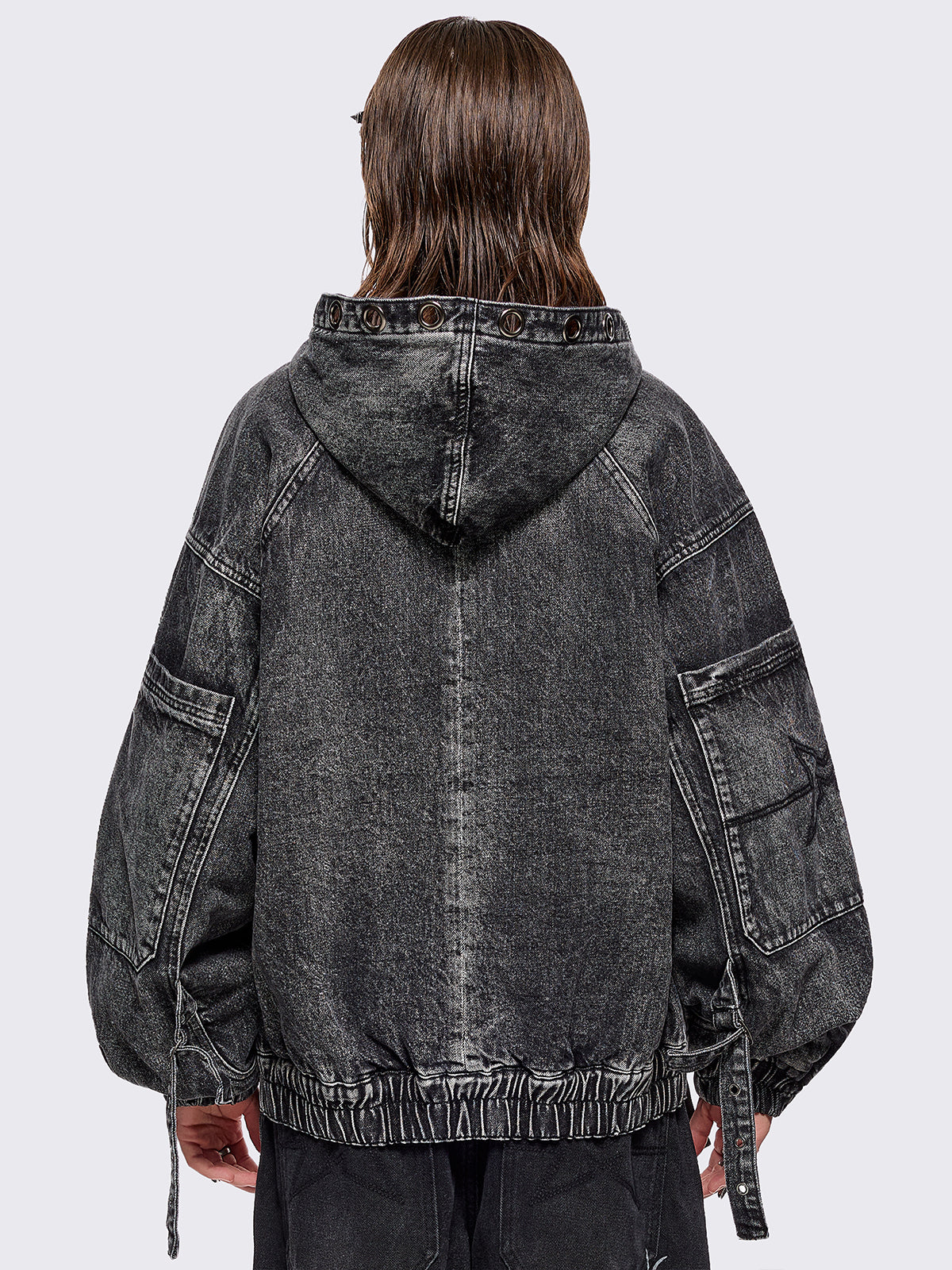 Black acid washed denim bomber jacket featuring boxy oversized fit, front flap pockets, buckle straps, eyelets, metal hardware and seams details.
