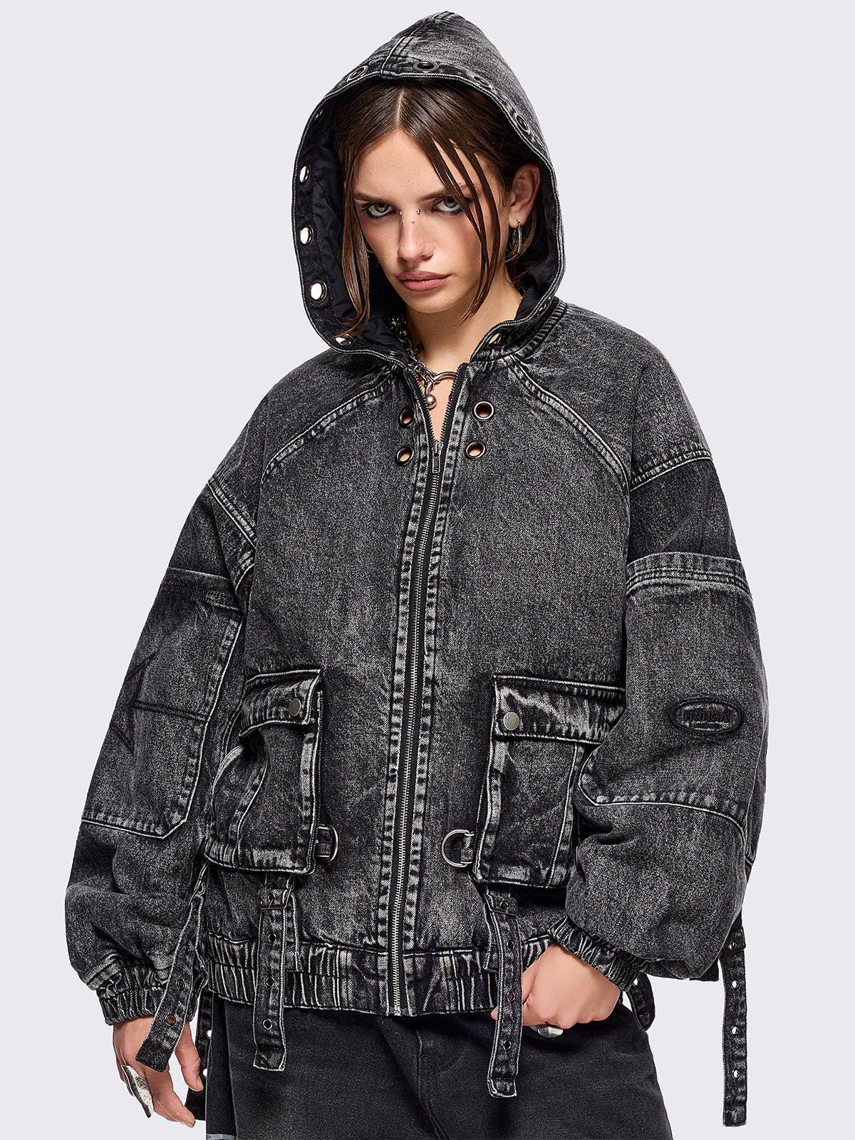 Black acid washed denim bomber jacket featuring boxy oversized fit, front flap pockets, buckle straps, eyelets, metal hardware and seams details.