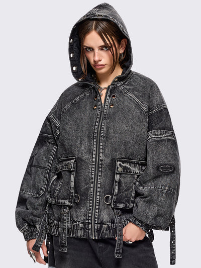 Black acid washed denim bomber jacket featuring boxy oversized fit, front flap pockets, buckle straps, eyelets, metal hardware and seams details.