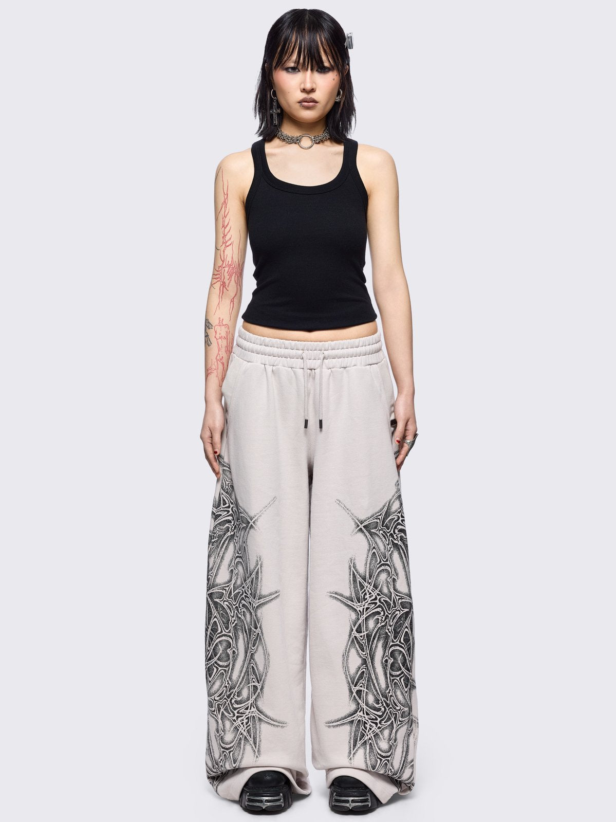 Grey wide leg sweatpants featuring a black sigilism graphic side print.