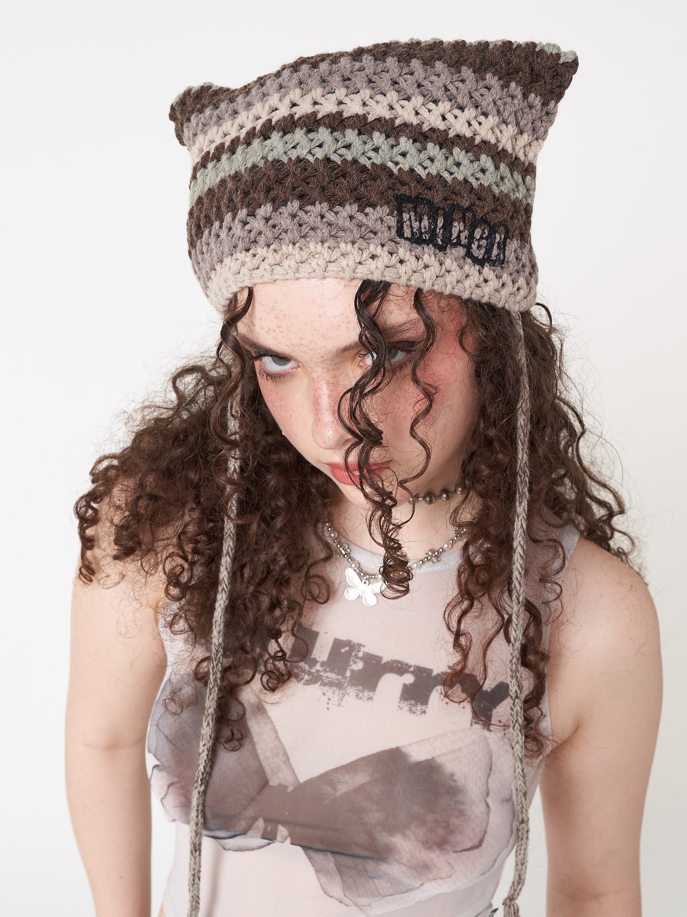 Knitted tie hat with all over stripes in green, brown and beige matching crochet style pattern and minga logo front embroidery